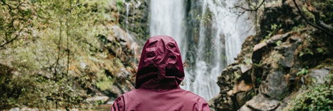 Burgundy raincoating fabric in front of a waterfall