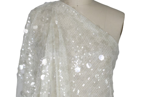 White sequin fabric draped over a mannequin on a white background